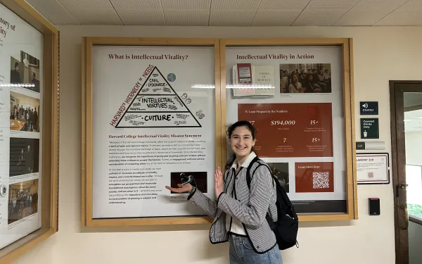 Ari standing next to the Intellectual Vitality display at Lamont Library, which she is a part of.
