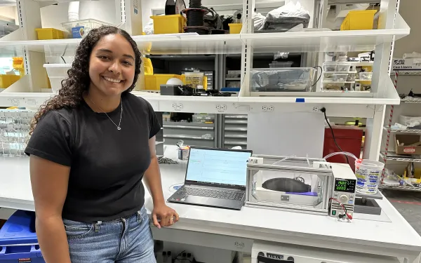 Senior Tiahna Padilla in the lab standing next to her thesis project.