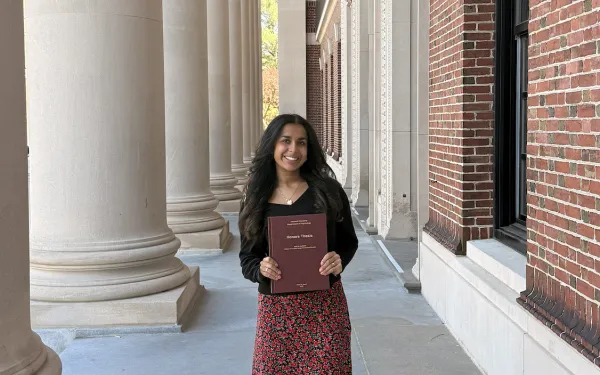 Gauri Sood '26 standing with her thesis papers in her hands.