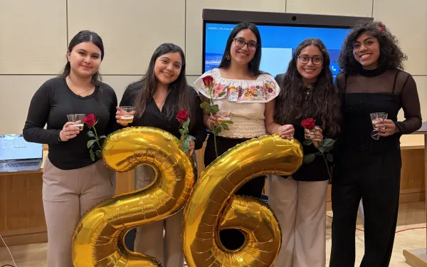 Lizbeth and four friends who just presented at the Latinx Senior Thesis Forum pose for a photo. Each person is holding a red rose.