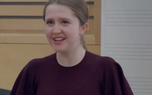 Student in a maroon dress sings during a thesis recital.