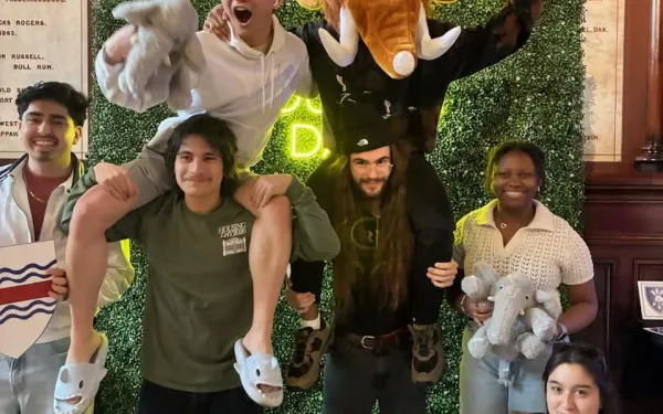 A group of first-years taking pictures in front of a housing day backdrop in Memorial Hall