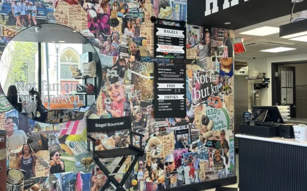 Inside of a bagel shop with a collage of picture, a mirror, and checkered floor tiles