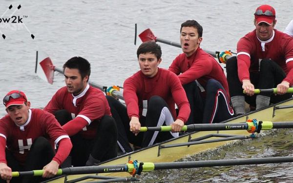 Students in crimson colored shirts rowing a boat