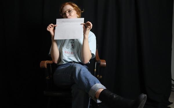 student in a chair and holding a piece of paper